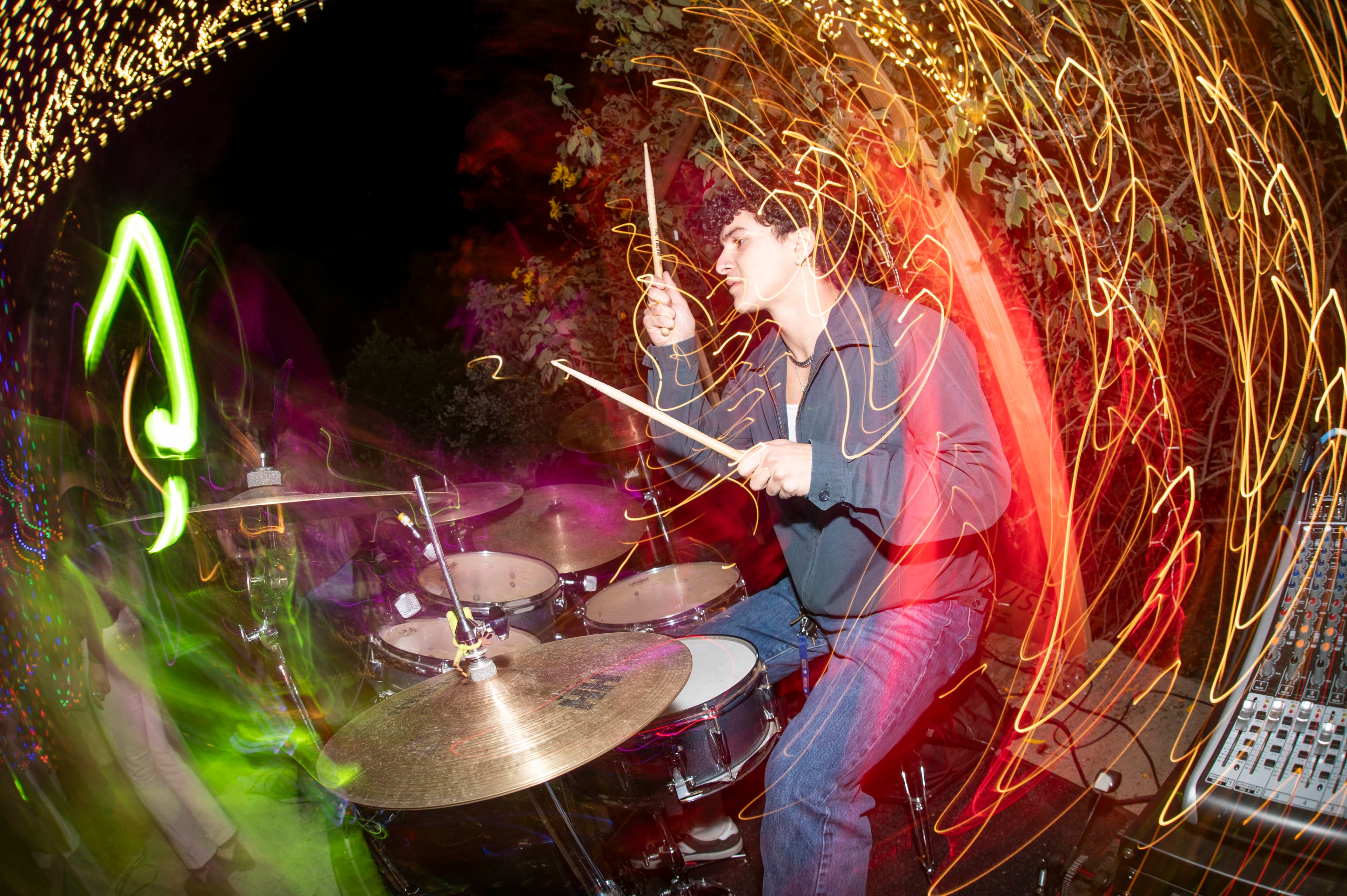 Ryan playing drums at an outdoor night performance surrounded by streaks of light