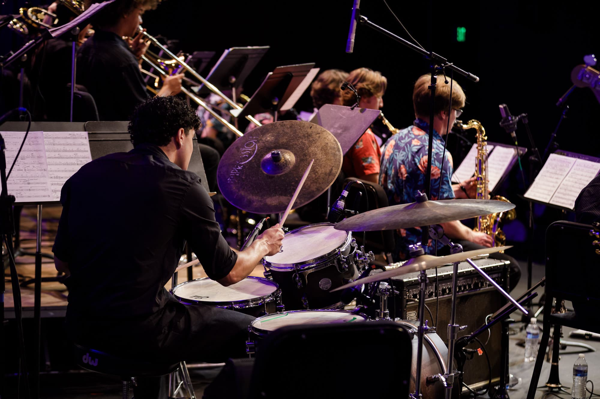 Ryan playing drums with a big band ensemble while reading a chart